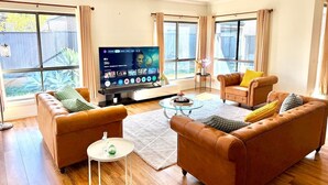 Una sala de estar con dos sofás, una mesa de centro y un televisor de pantalla plana.