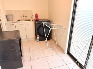Cocina pequeña con lavadora, tendedero y lavaplatos.