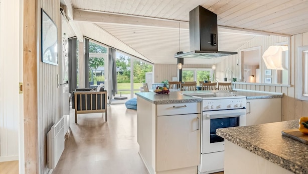Una cocina moderna con una isla central, una estufa y un ventanal con vistas al exterior.