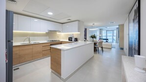 Eine moderne Küche mit einer zentralen Kochinsel, weißen Schränken und einem Essbereich mit einem weißen Sofa und Tisch.