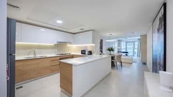 A modern kitchen with a central island, white cabinetry, and a dining area with a white sofa and table.