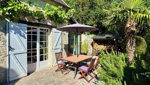A stone patio with a table and chairs, a covered outdoor area, and a stone wall. - La Maison des Roses - A charming house with a garden (Rully)