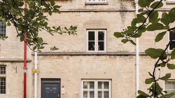 A two-story stone building with a dark-colored door, a small window with shutters, and a visible number '3' on the wall.