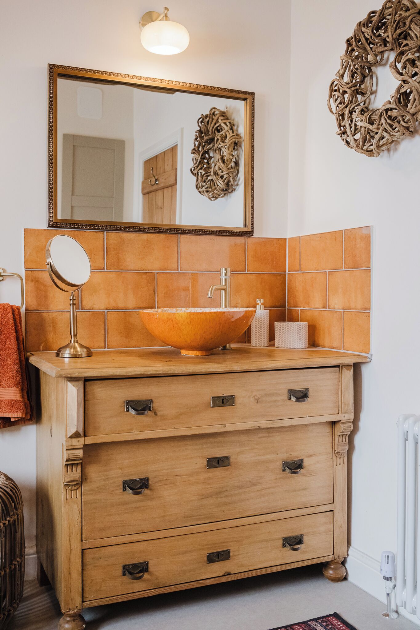 A bathroom with a wooden vanity, a large mirror, a vessel sink, and a towel rack.