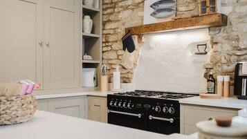 A kitchen with a stone wall, wooden shelf, and a stove.