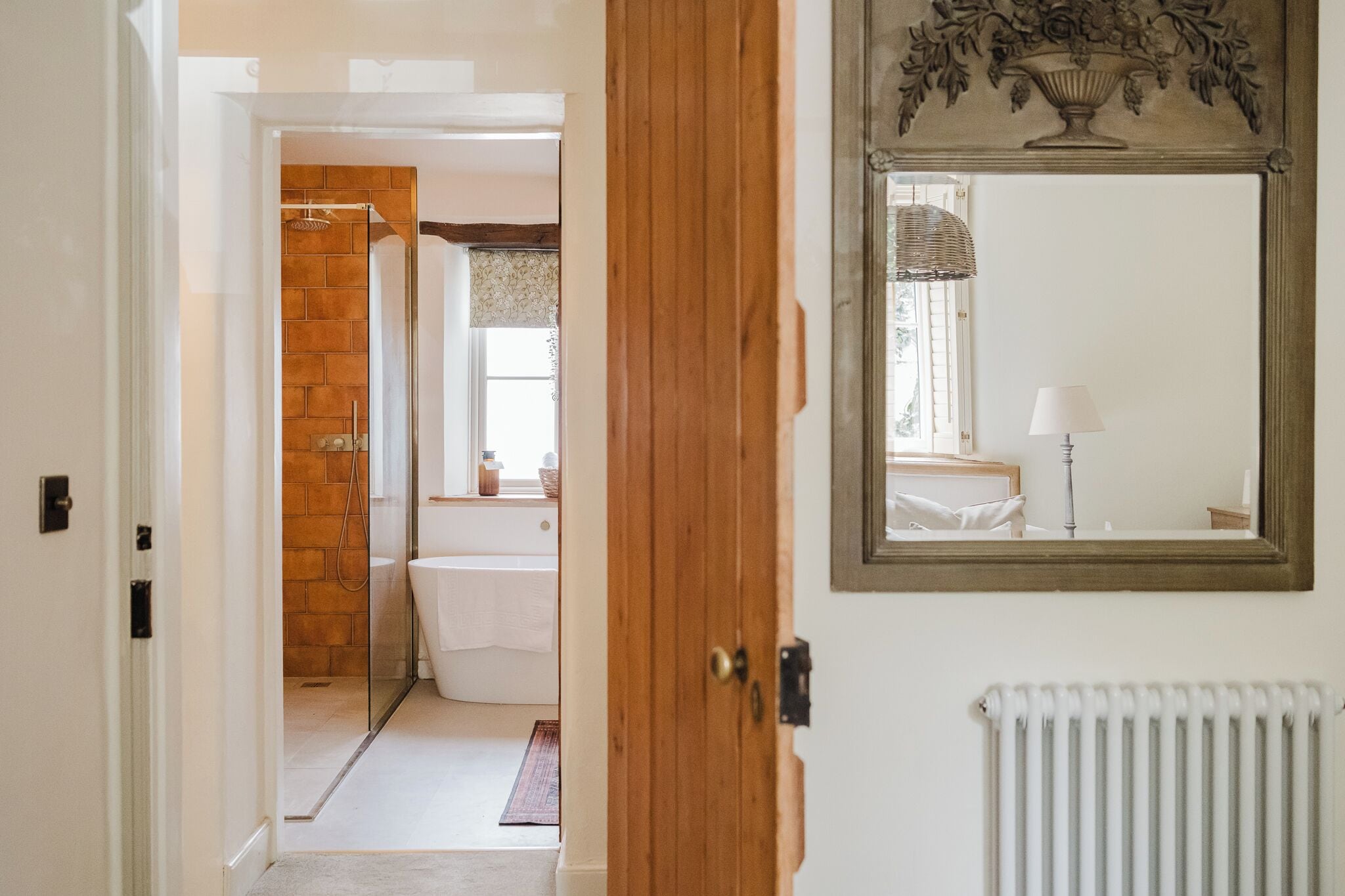 A bathroom with a shower, toilet, and a mirror with a decorative frame.