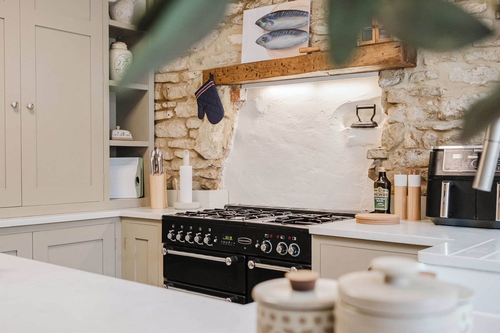 Una cucina con un fornello a gas, mensole in legno e parete in pietra.