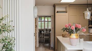 A kitchen with a white countertop, a vase with flowers, and a hanging light fixture.