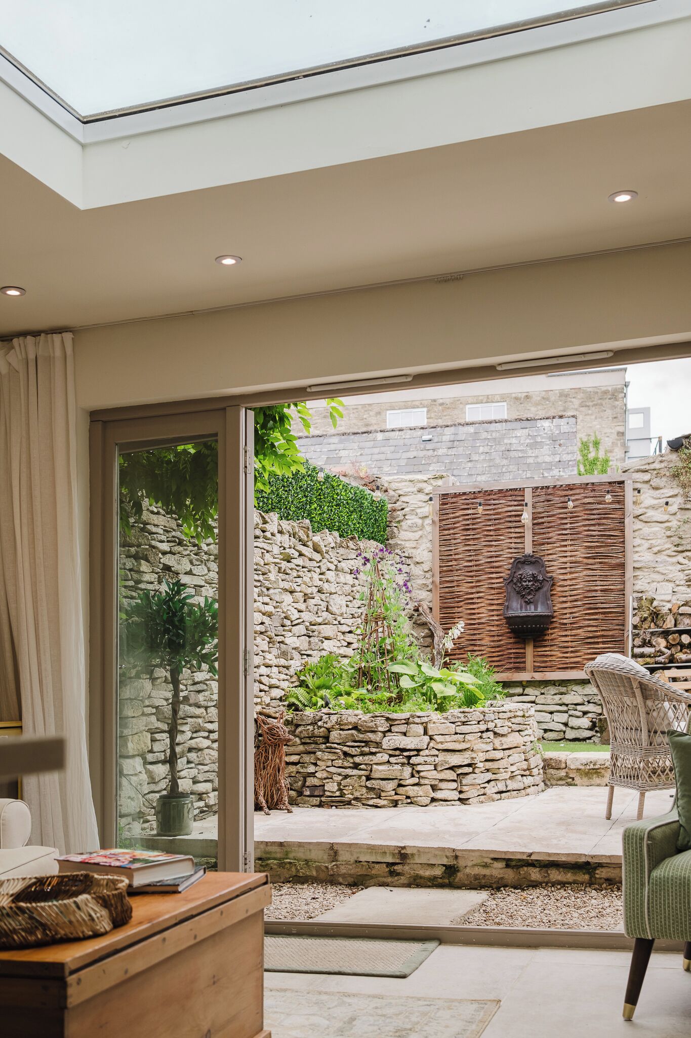 A modern interior with a glass door leading to a stone wall garden.