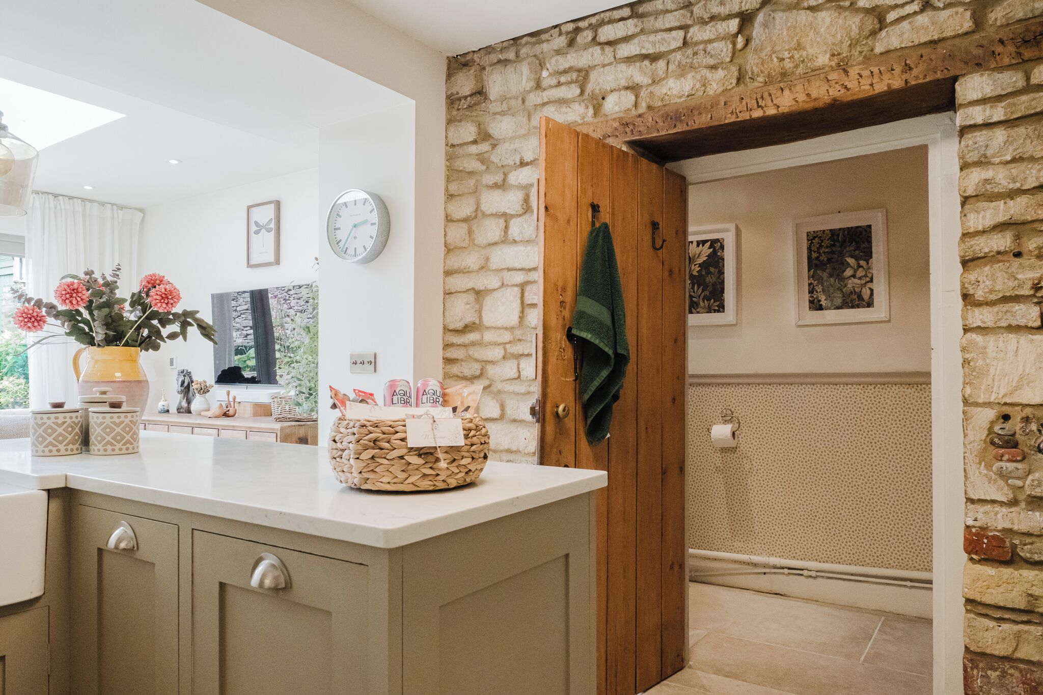 A kitchen with a stone wall, wooden door, and a clock on the wall.