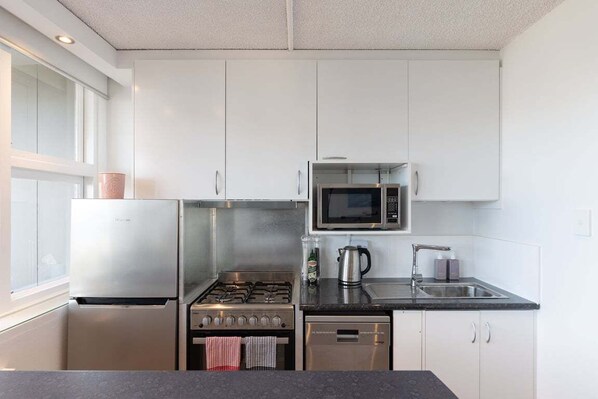 A modern kitchen with stainless steel appliances, a microwave, and a gas stove.