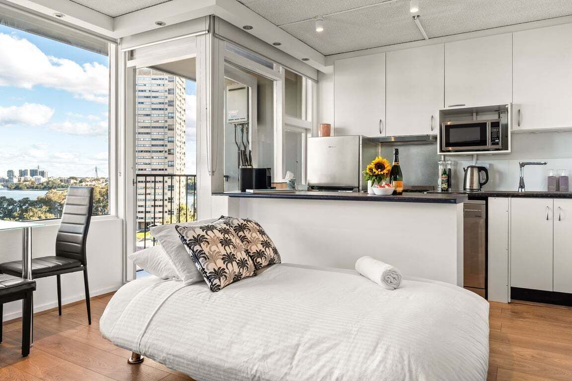 A modern bedroom with a bed, a chair, and a view of the city.