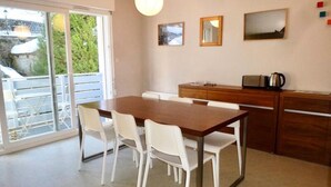 A dining area with a table and chairs, a kitchen counter, and a sliding glass door leading to an outdoor area. - Oustal Residence for Eight People (Bareges)