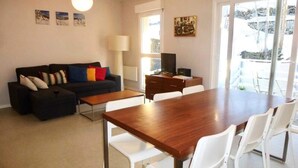 A living room with a sofa, coffee table, TV, and a dining area with chairs and a table. - Oustal Residence for Eight People (Bareges)