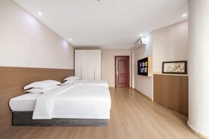 Una habitación de hotel con cama, armario, televisor y un cuadro en la pared.