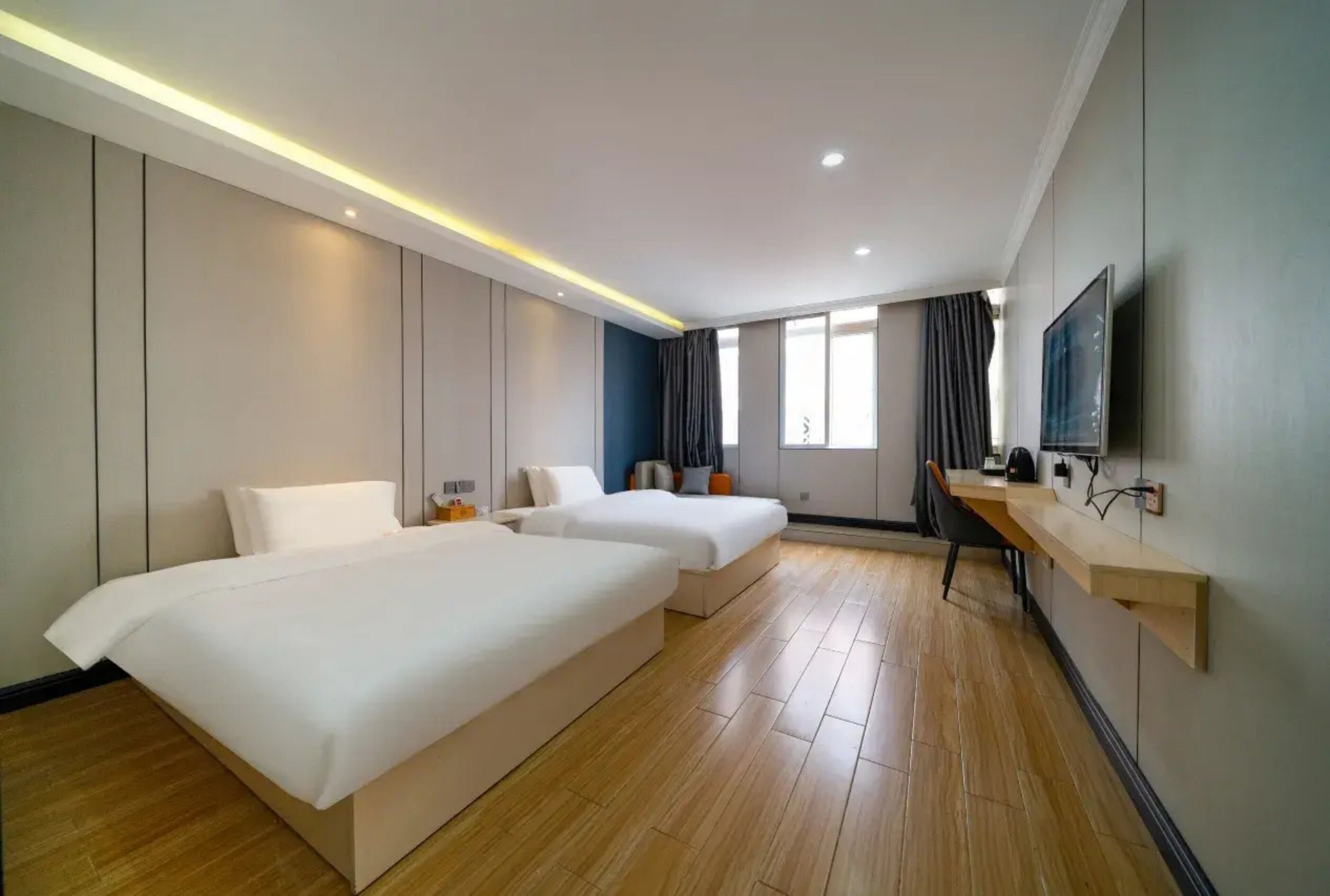 Habitación de hotel con dos camas, televisión, escritorio y un ventanal grande.