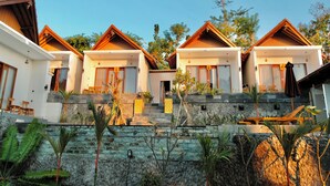 A row of modern, two-story cottages with stone steps leading up to the entrance, surrounded by tropical plants.