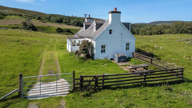 A white house with a chimney, surrounded by a fenced yard and a gravel path. - Strathnoon by Interhome (Tomatin)