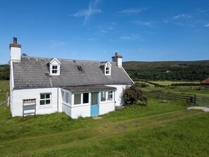 A white house with a blue door, a small porch, and a chimney. - Strathnoon by Interhome (Tomatin)