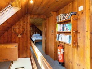 A wooden cabin with a loft bedroom, a bookshelf, and a fire extinguisher. - Strathnoon by Interhome (Tomatin)