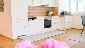 A modern kitchen with white cabinets, a built-in oven, and a microwave. - Villa Rebgarten (Höchst)