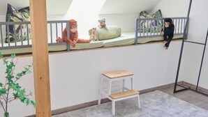 A room with a sloped ceiling, a small white bench, a grey rug, a wooden plant stand, and a metal ladder. - Villa Rebgarten (Höchst)
