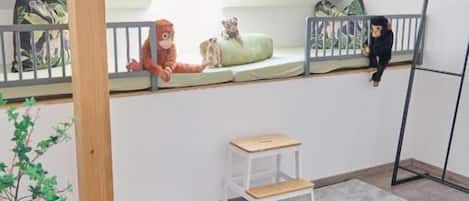 A room with a sloped ceiling, a small white bench, a grey rug, a wooden plant stand, and a metal ladder.