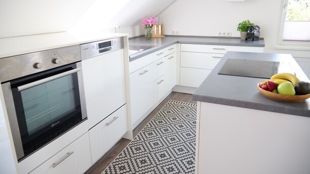 A modern kitchen with white cabinetry, a built-in oven, and a fruit bowl on the counter. - Villa Rebgarten (Höchst)