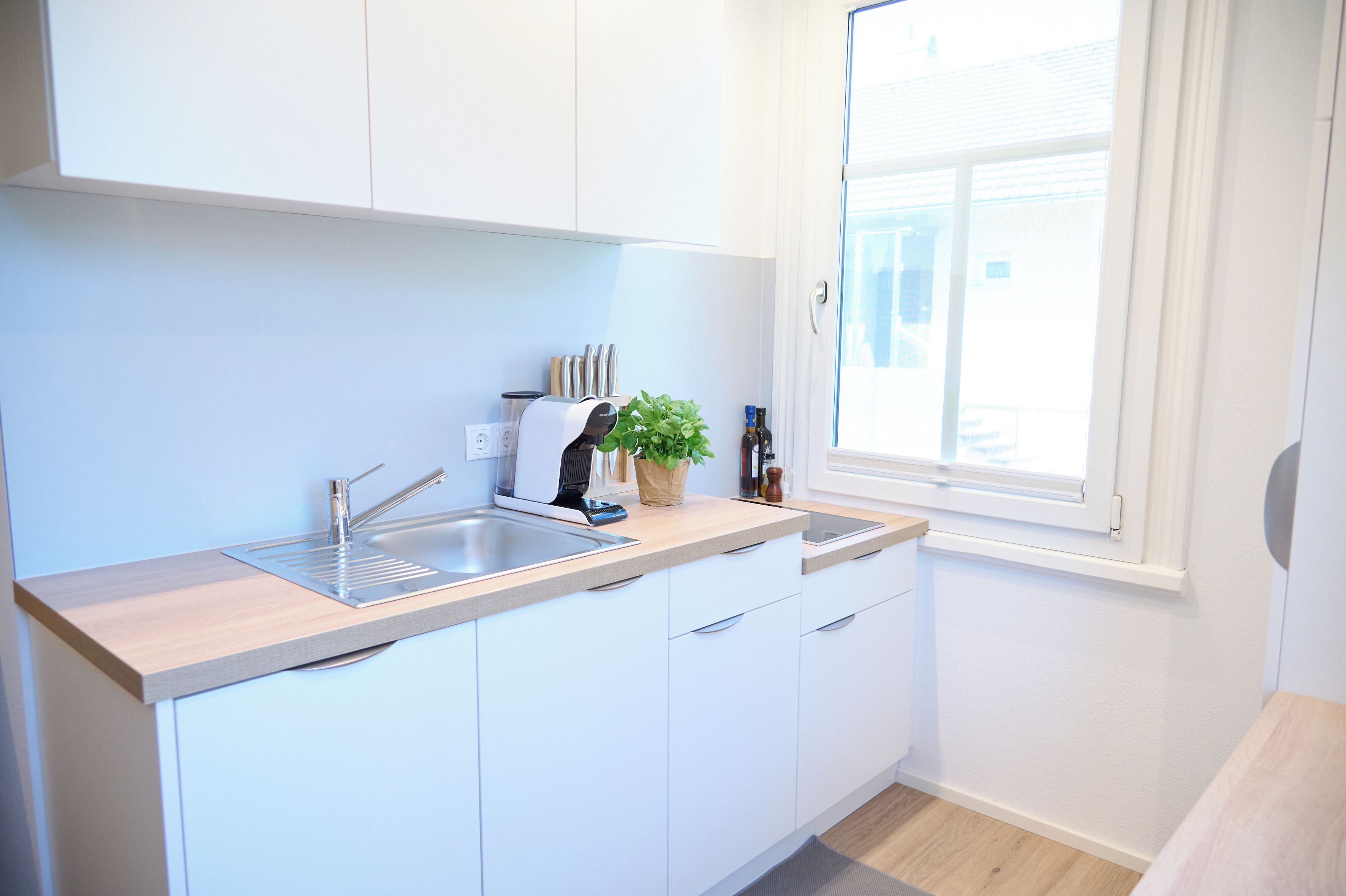 A modern kitchen with a sink, countertop, and window.