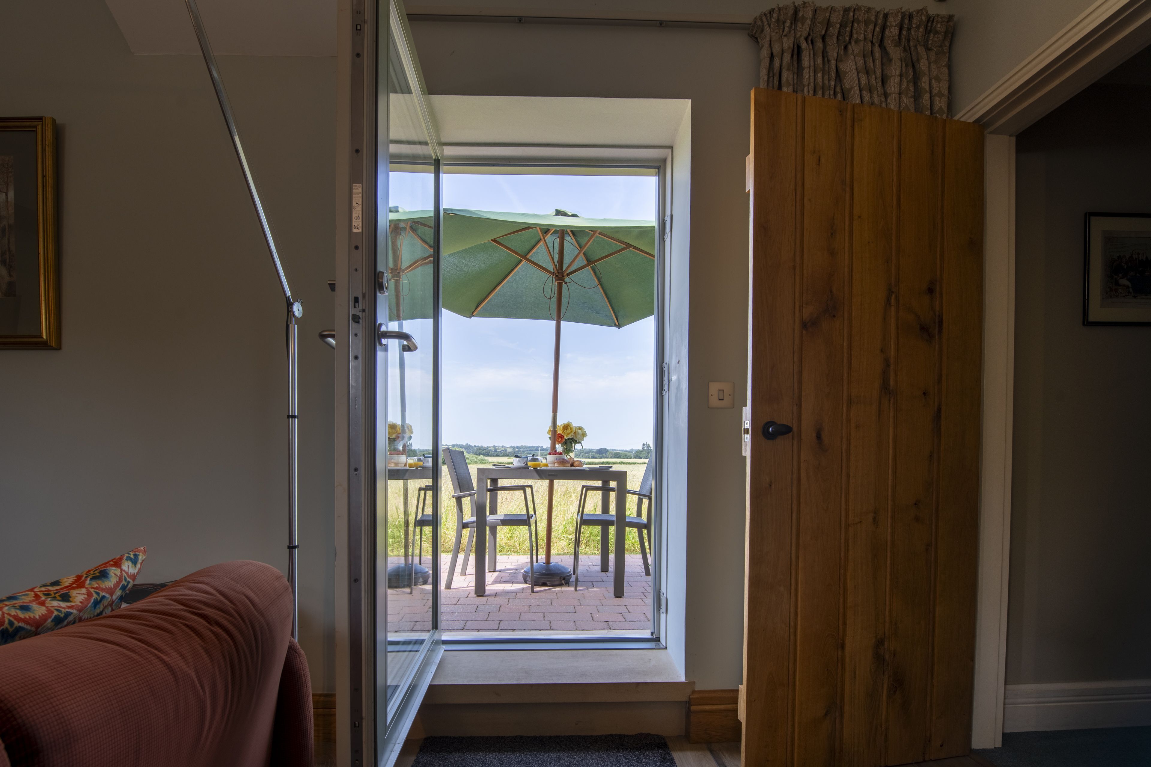 An open door leading to a patio with a table, chairs, and an umbrella.