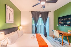 A hotel room with a bed, a desk, a chair, a ceiling fan, and a wall-mounted TV. - Glendale Stadium Retreat  Pool, Gym & Westgate AZ (Glendale)