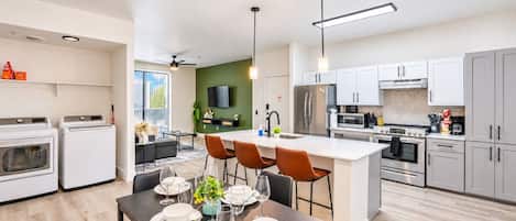 A modern kitchen with a central island, built-in appliances, and a dining area with a table set for four.