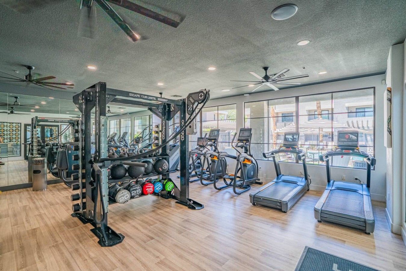 Une salle de sport équipée de machines d’exercice, de tapis de course et dotée d’un mur recouvert de miroirs.
