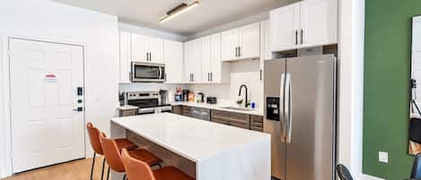 A modern kitchen with white cabinets, stainless steel appliances, and a marble island.