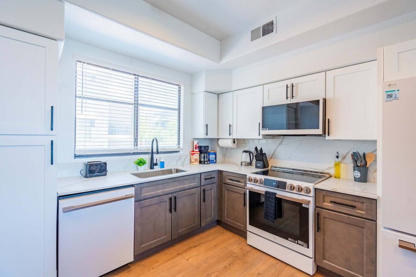 A modern kitchen with white cabinets, a microwave, an oven, and a toaster.