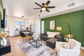 Een moderne woonkamer met een bank, salontafel en een eethoek met stoelen.