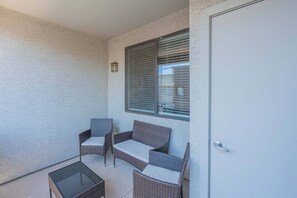 A balcony with wicker furniture and a glass table. - Westgate Stadium Stay  Pool Gym WD Parking (Glendale)