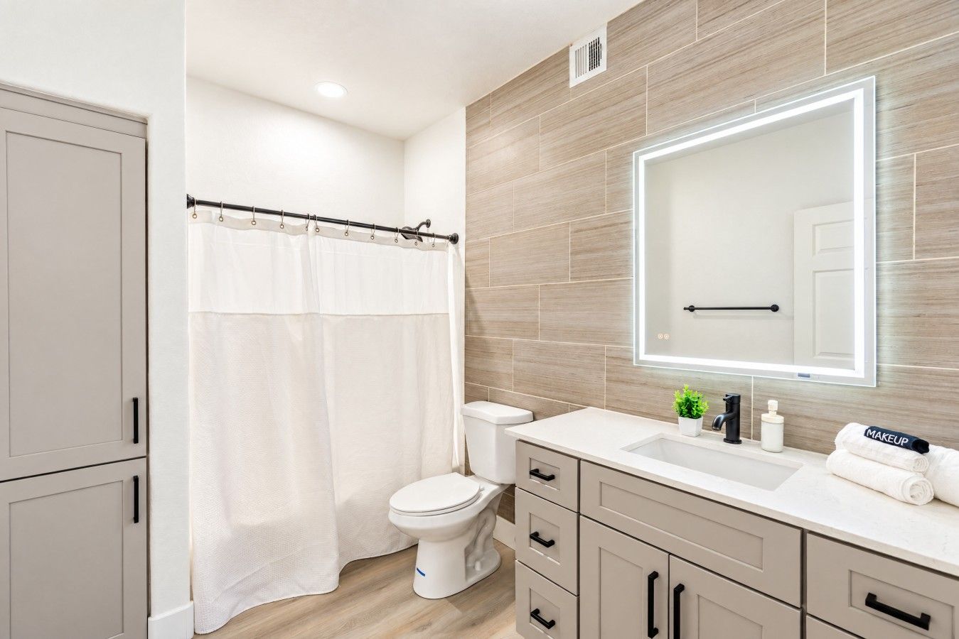 Un baño moderno con inodoro, lavamanos y espejo.