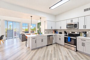 A modern kitchen with white cabinets, stainless steel appliances, and a large island. - Glendale Westgate Stay  Pool Gym WD Near Stadium (Glendale)