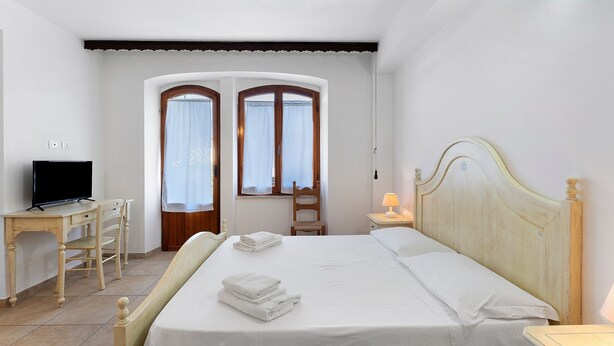 Ein Schlafzimmer mit einem Bett, einem Schreibtisch mit Fernseher und einem Stuhl.