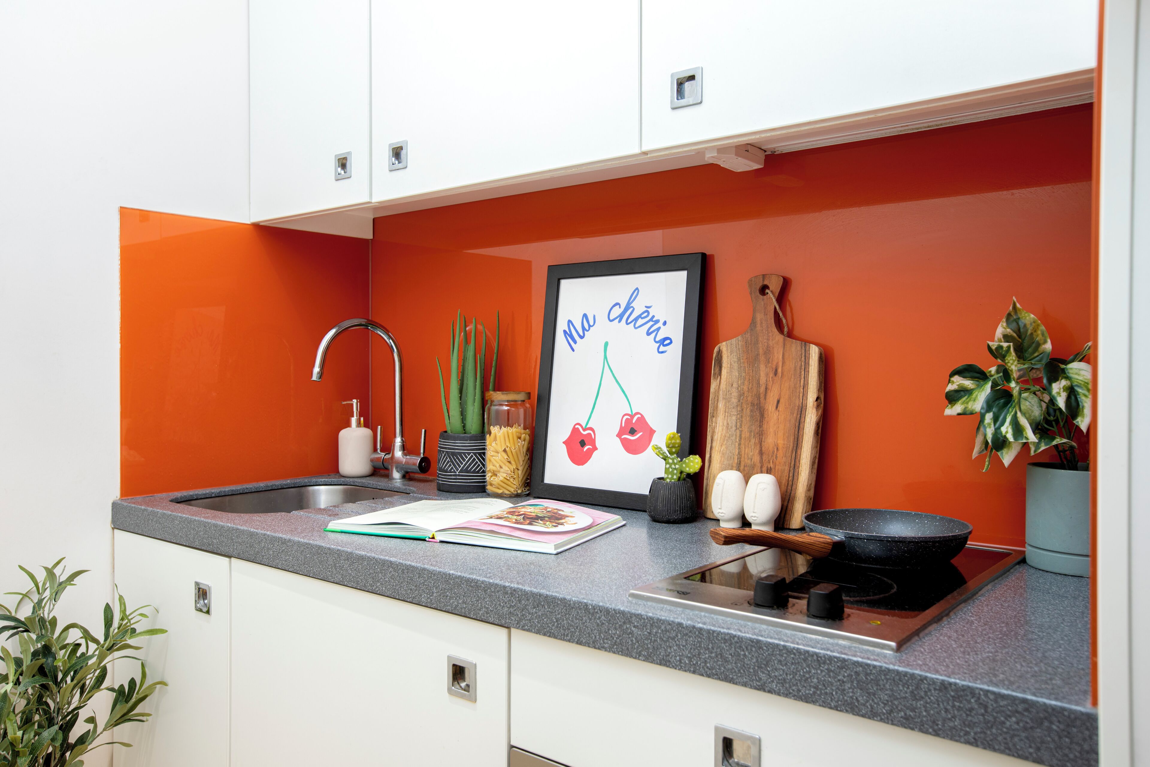 A kitchen with a sink, faucet, countertop, and a framed picture with text.