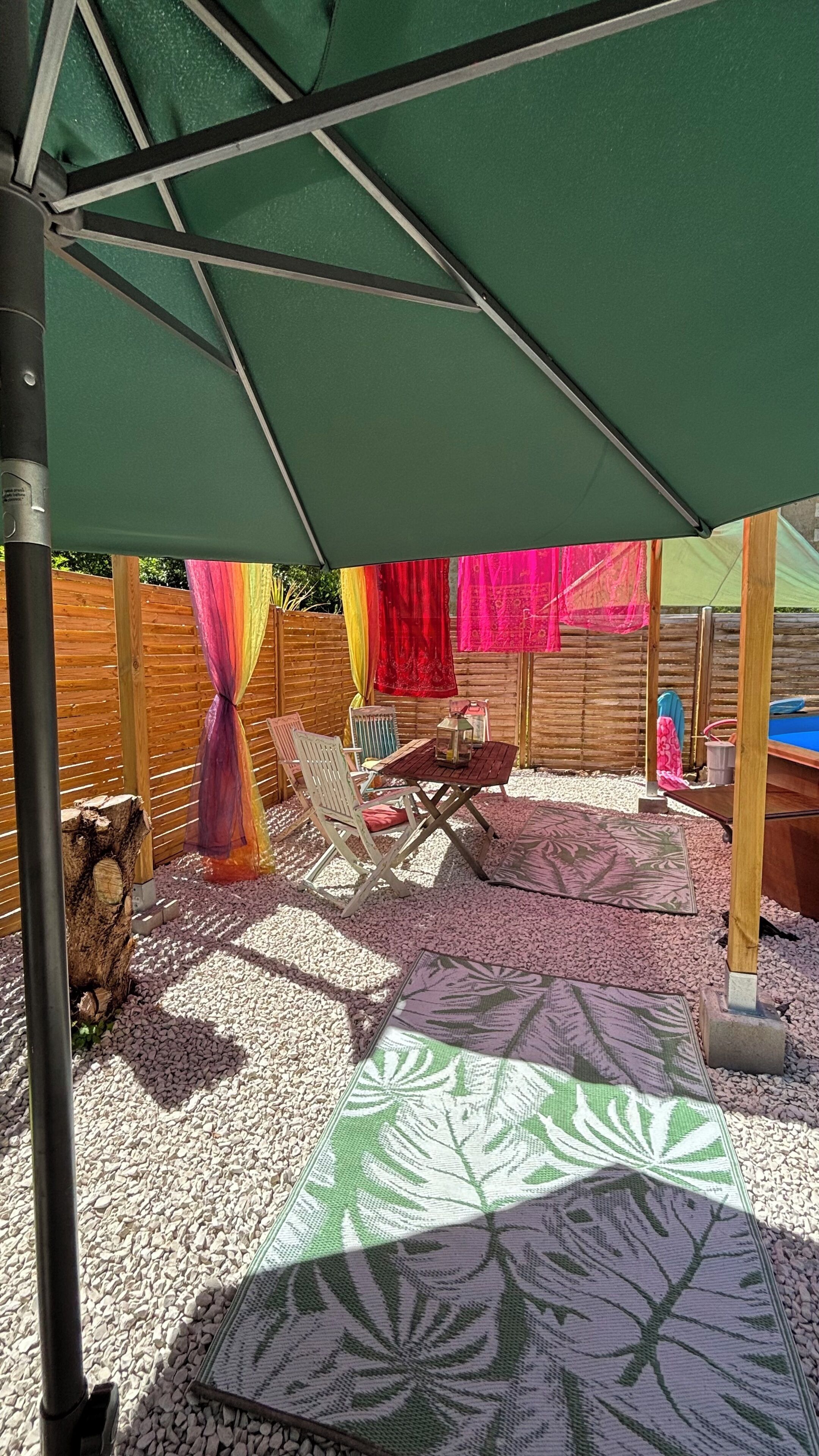 Un patio con un paraguas verde, una mesa de madera y una mesa de billar.