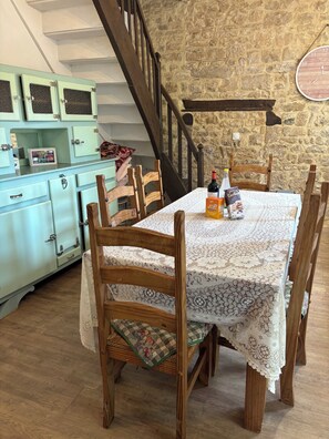 A dining table with a lace tablecloth, wooden chairs, and a bottle of wine. - Cosy bright cottage perfect for families or some time in nature. Private pool! (Cellefrouin)