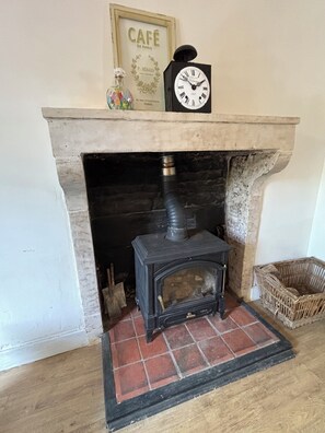 A fireplace with a clock above it, a framed sign above the fireplace, and a wicker basket to the right. - Cosy bright cottage perfect for families or some time in nature. Private pool! (Cellefrouin)