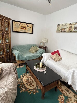 A room with a bed, a chair, a table with candles, a lamp, and a framed picture on the wall. - Cosy bright cottage perfect for families or some time in nature. Private pool! (Cellefrouin)
