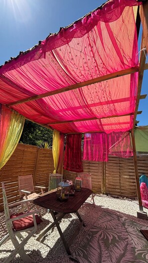 A covered outdoor seating area with chairs and a table, surrounded by wooden fences and a decorative canopy. - Cosy bright cottage perfect for families or some time in nature. Private pool! (Cellefrouin)