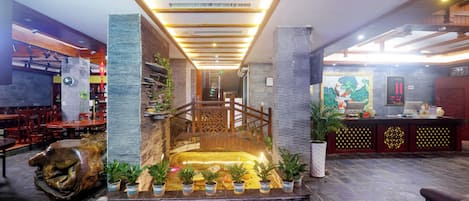 Un hall d’entrée avec un comptoir de réception, un escalier et des plantes en pot.