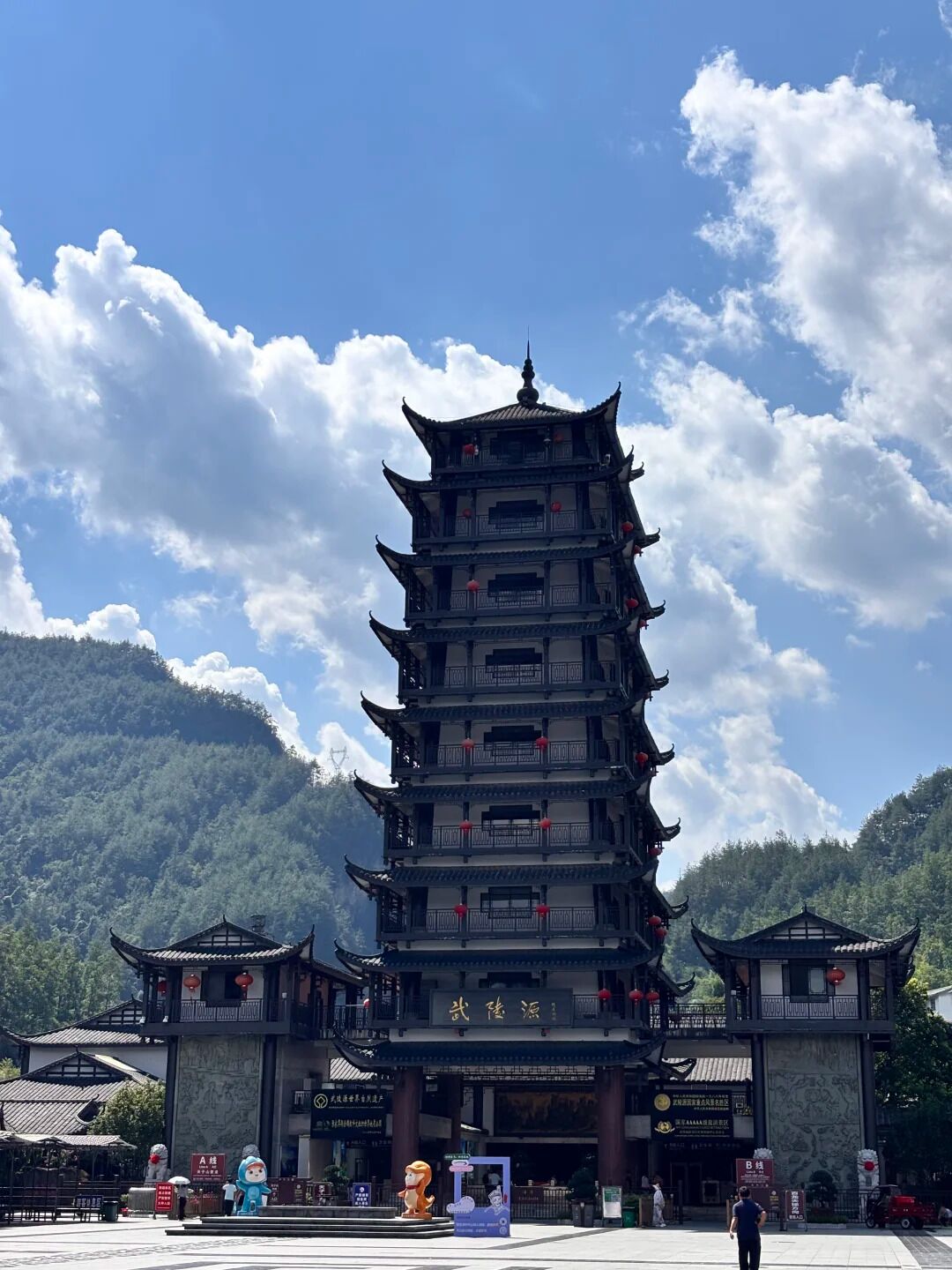 Une pagode traditionnelle à plusieurs niveaux, avec un ciel dégagé et des montagnes en arrière-plan.