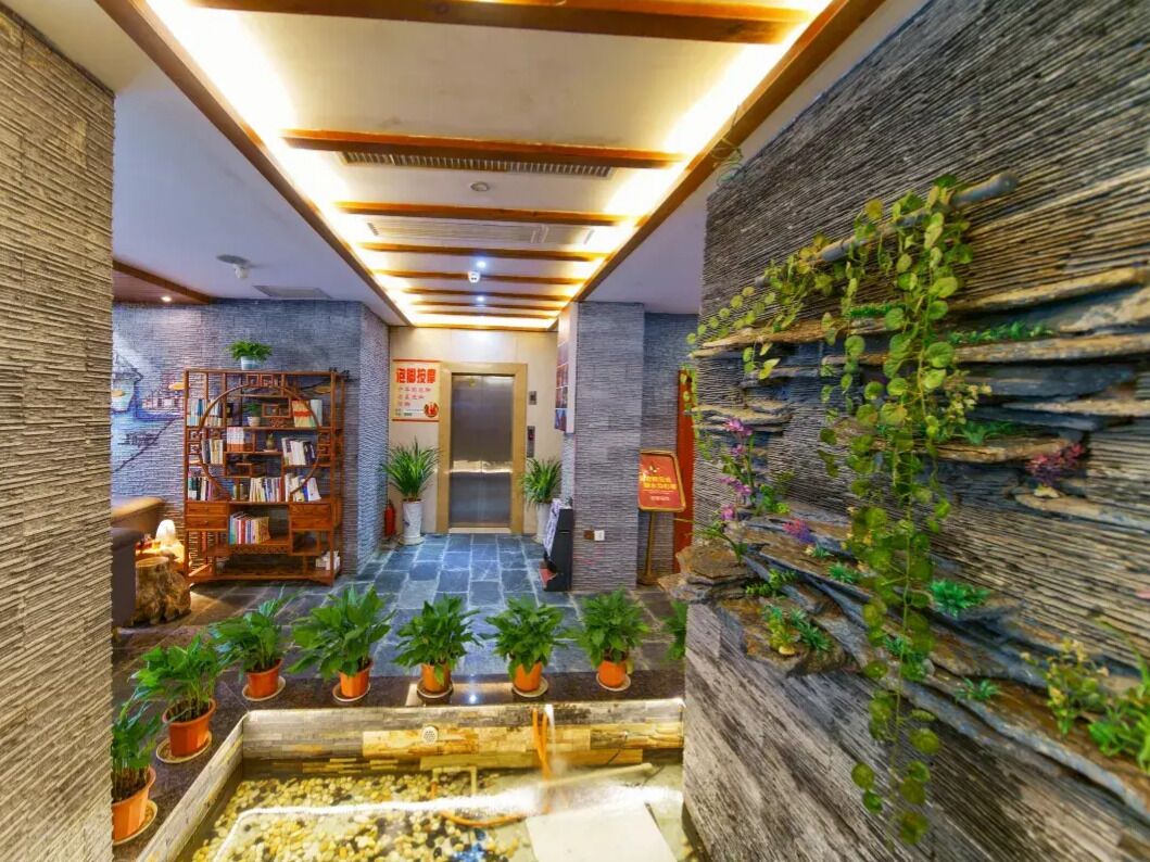 Un hall d’hôtel avec un comptoir d’accueil en bois, une bibliothèque et une jardinière murale.