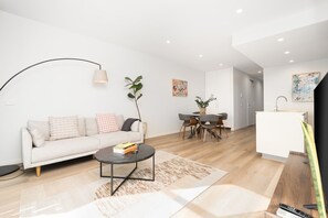 A modern living room with a sofa, coffee table, dining table, and chairs.